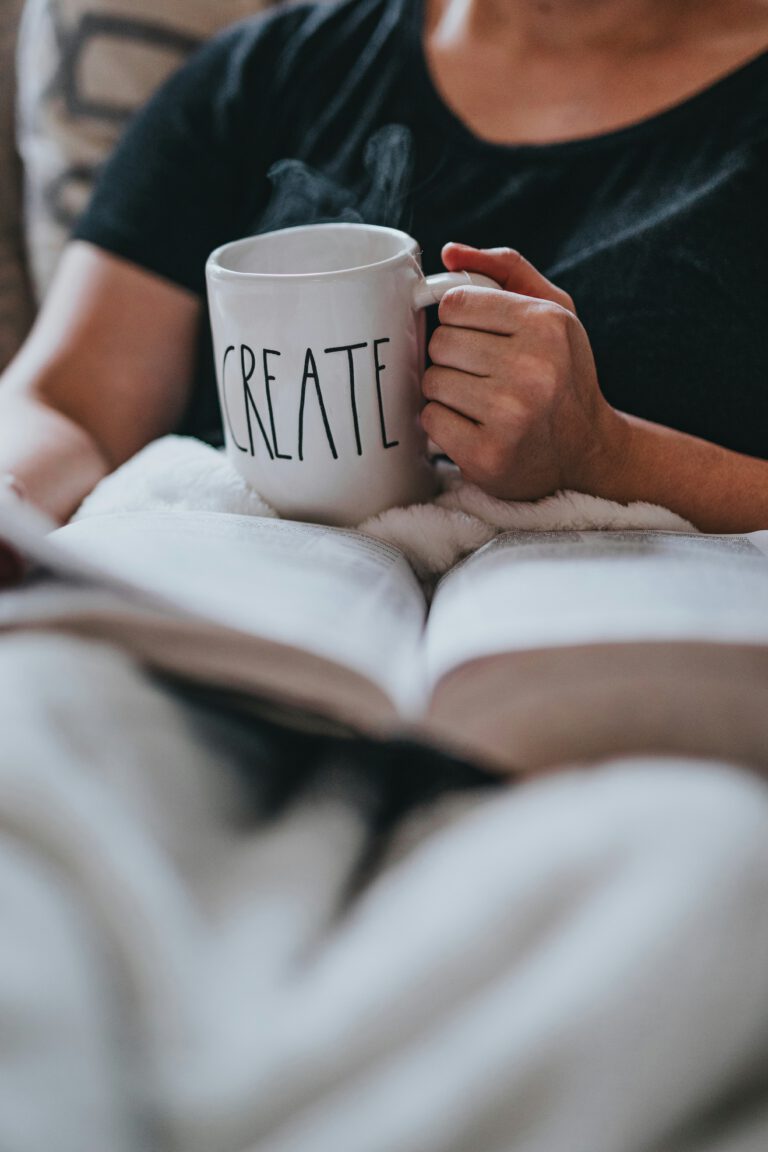 girl holding coffee cup above an open book